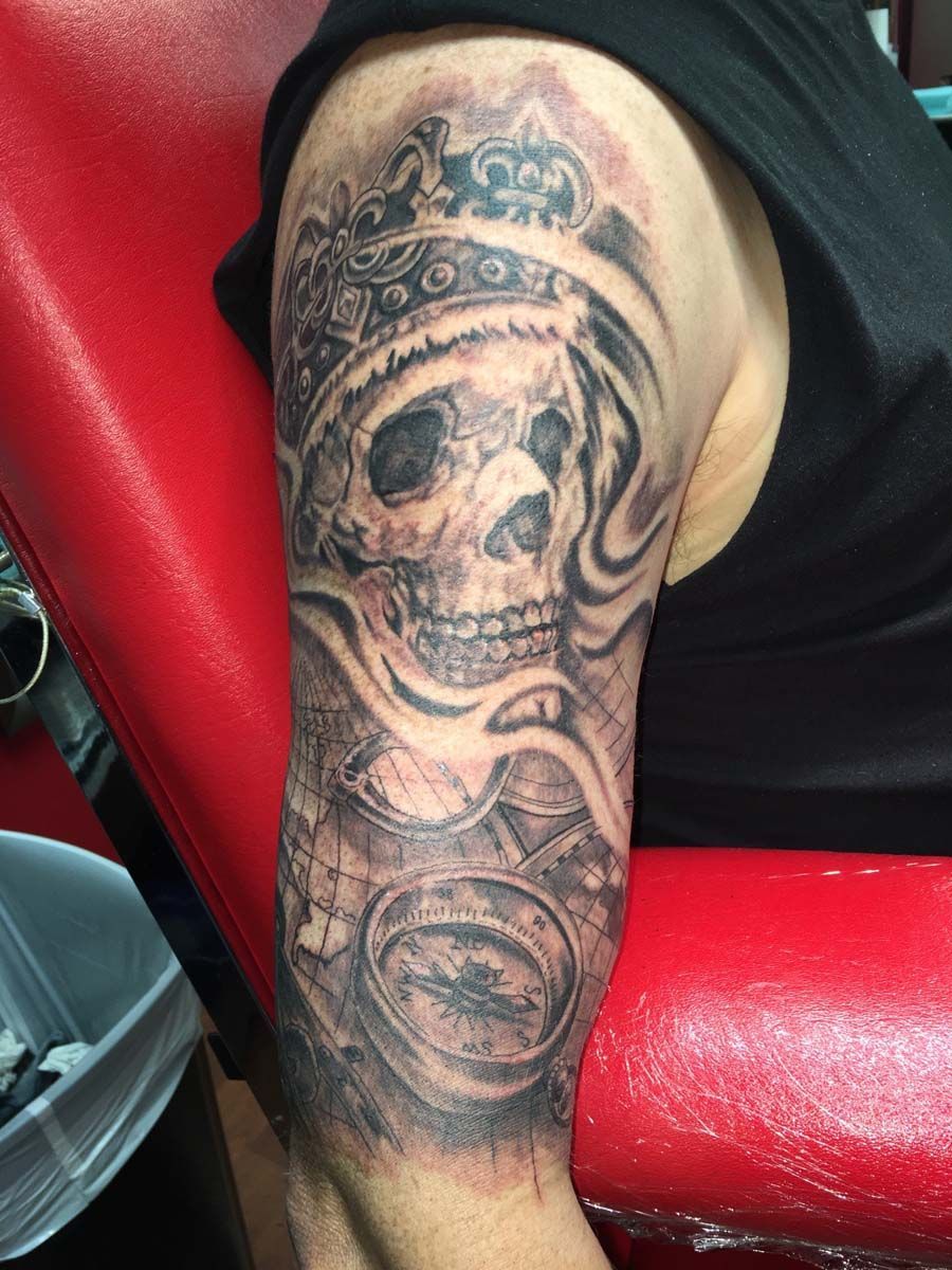 A man has a tattoo of a skull with a crown on his arm.