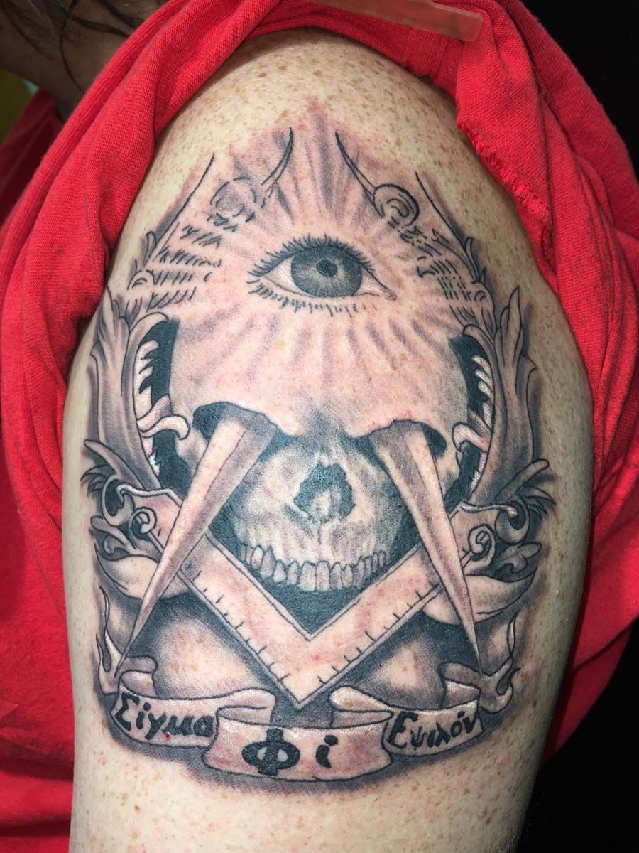 A tattoo of a skull with an all seeing eye and a masonic symbol