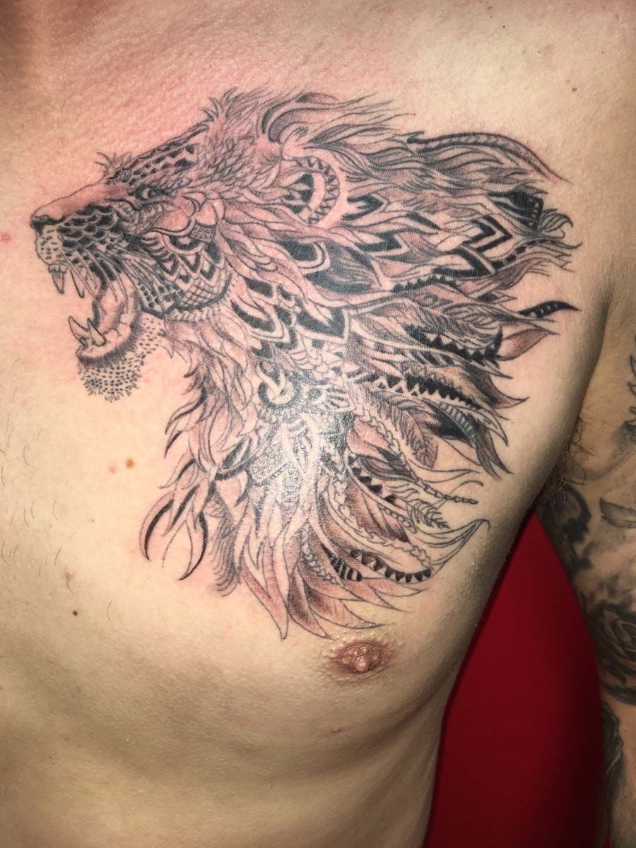 A man has a tattoo of a lion 's head on his chest.