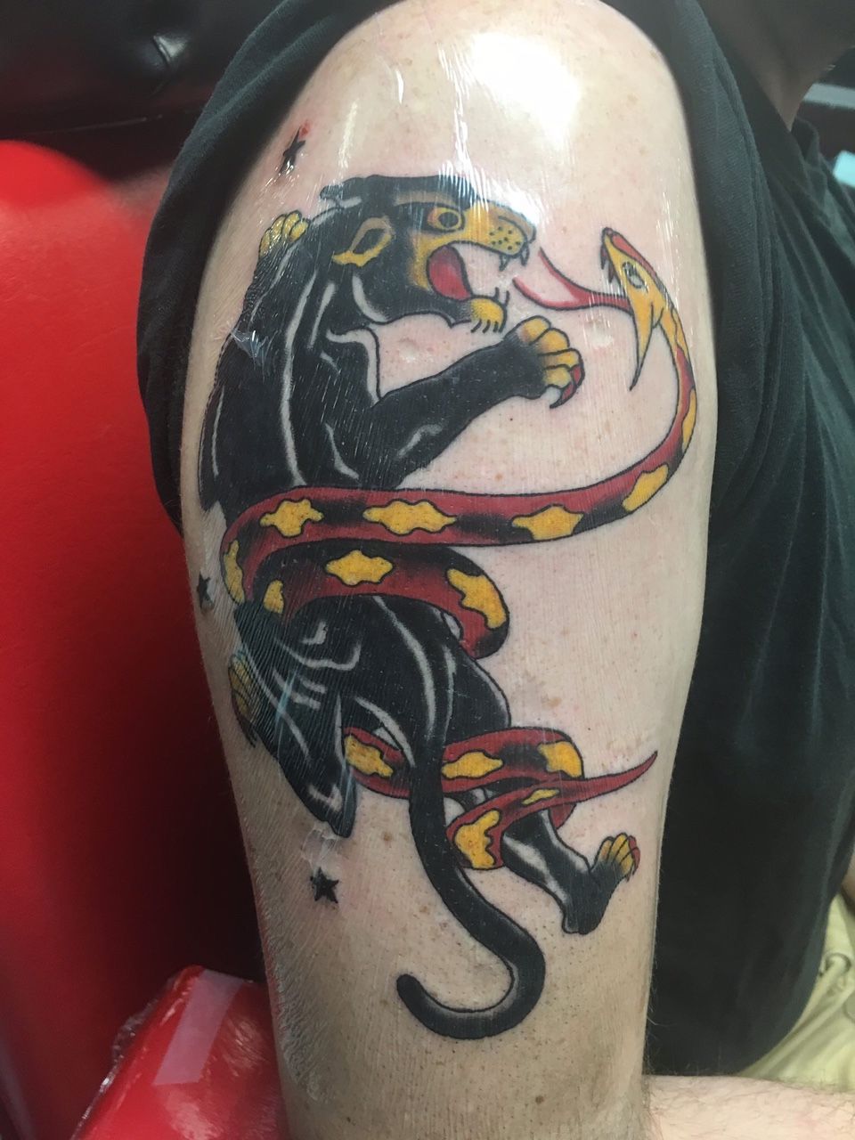 A tattoo of a panther with a snake around its neck