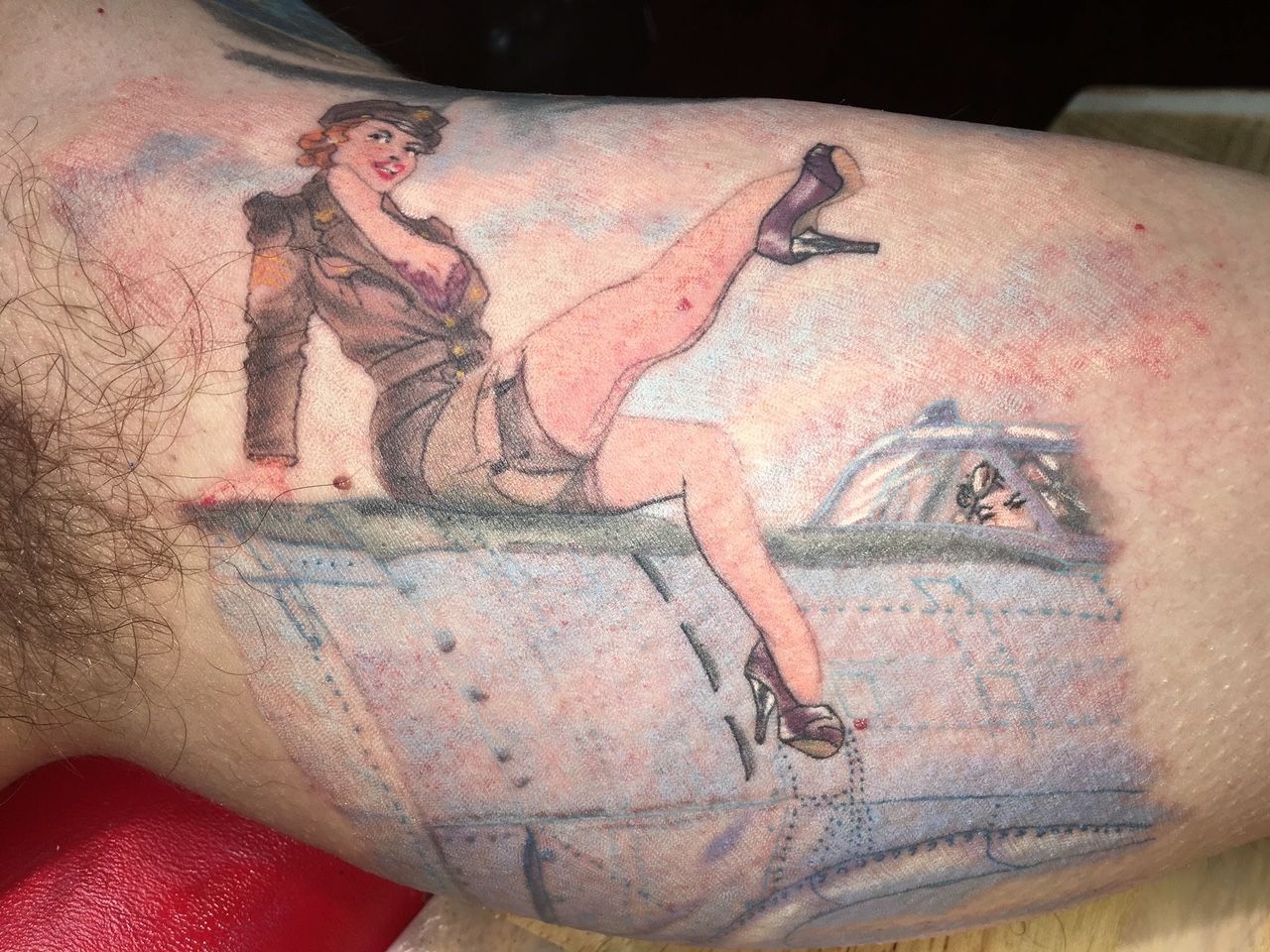 A man has a pin up girl tattoo on his arm.