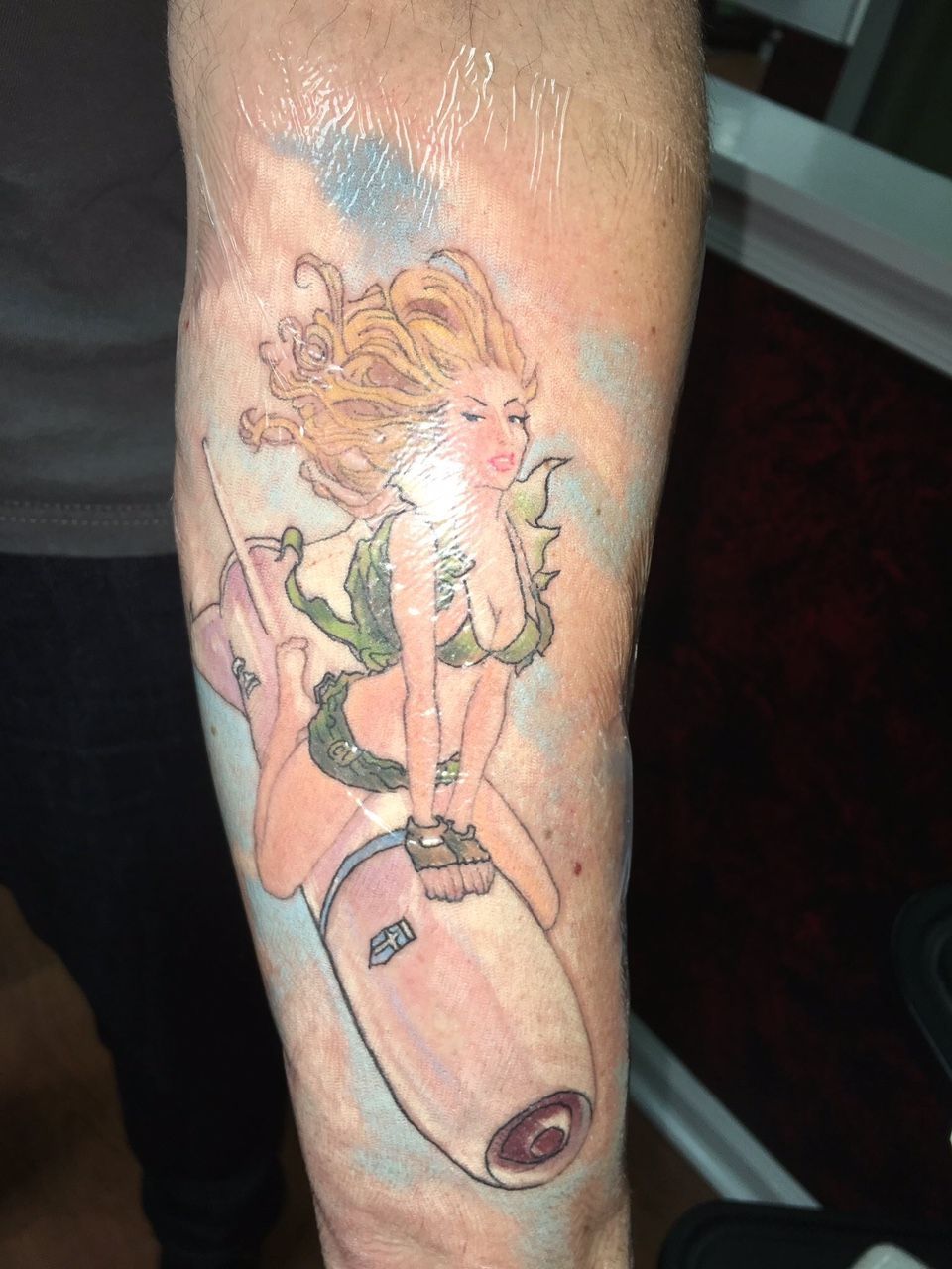 A blonde woman riding a rocket tattoo