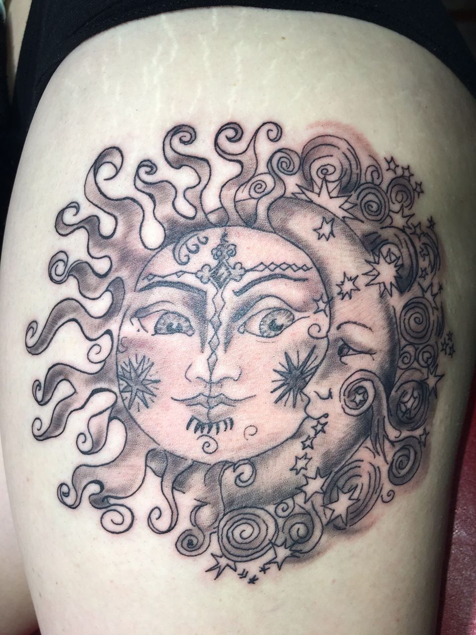 A woman has a tattoo of the sun and moon on her leg