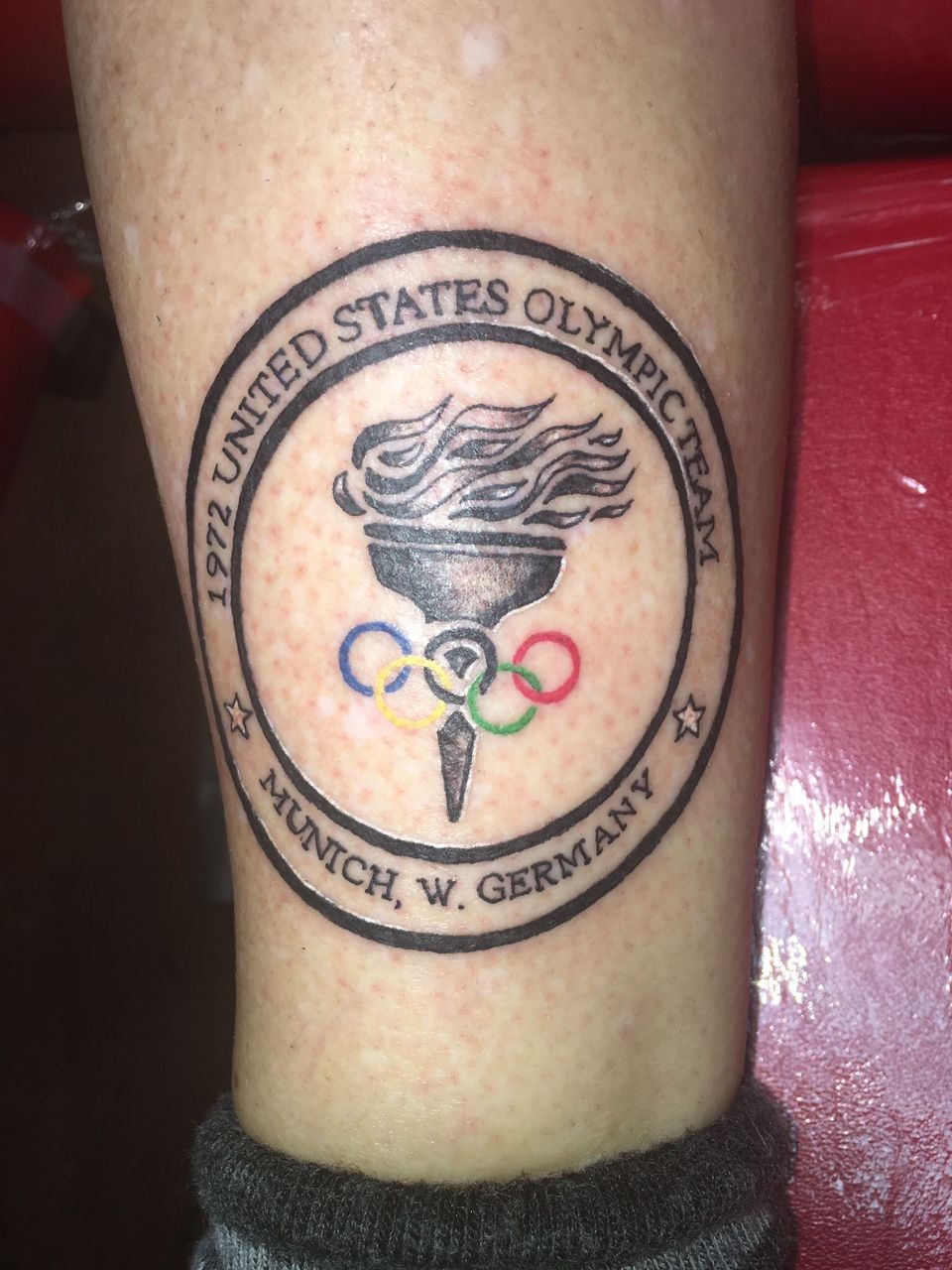 A person has a united states olympics logo tattooed on their leg