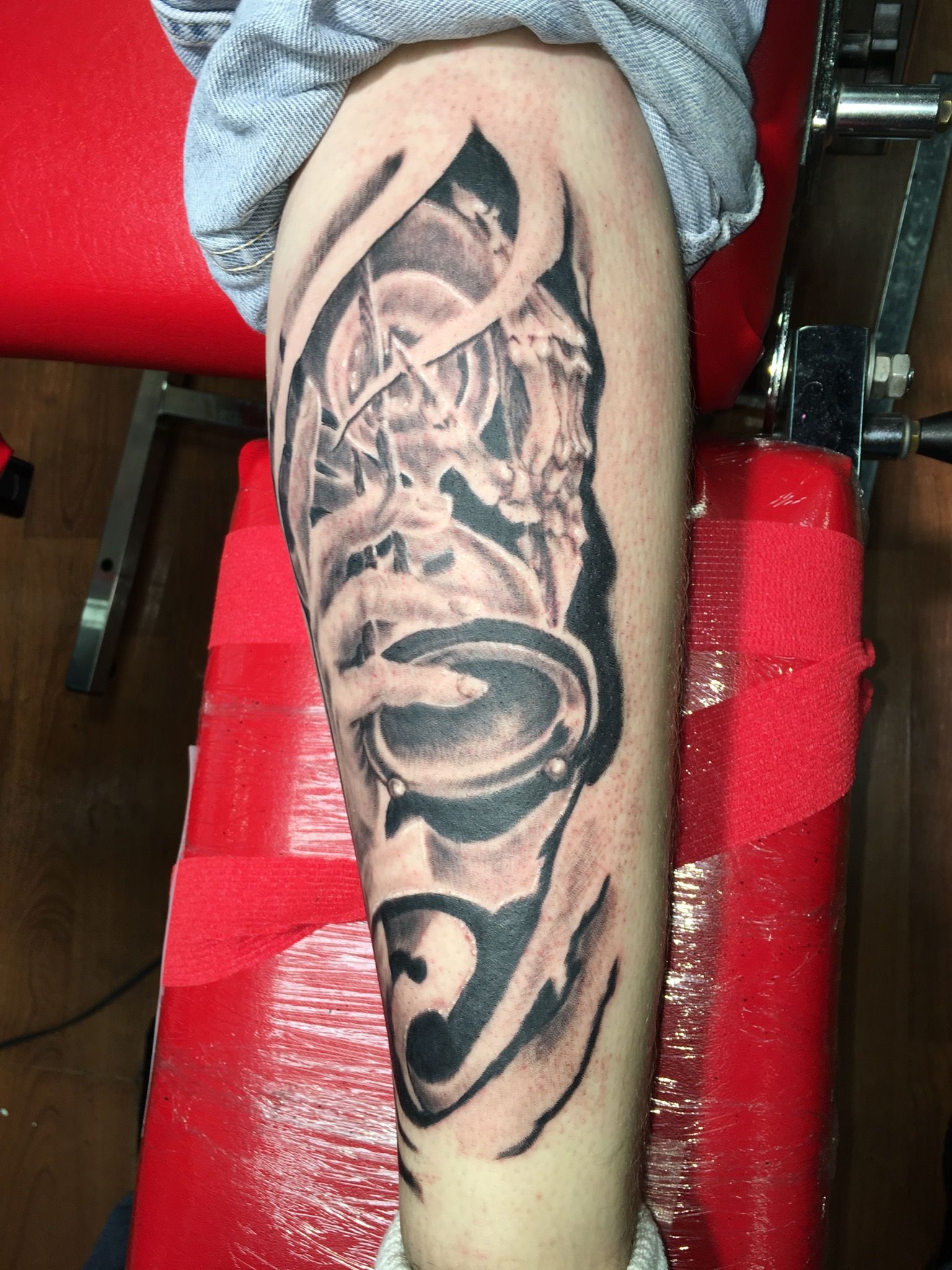 A person with a tattoo on their leg is sitting on a red chair.
