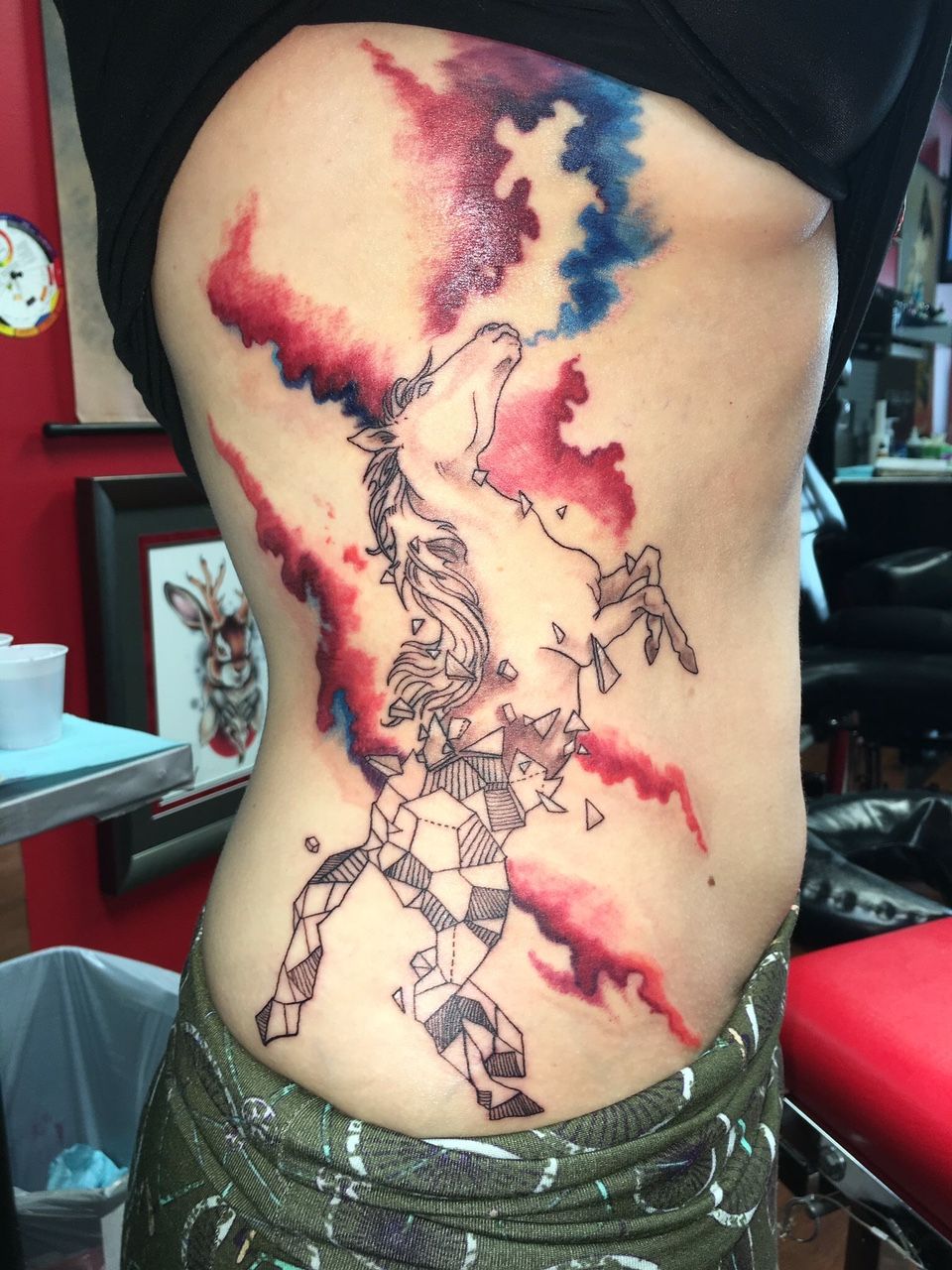 A woman has a tattoo of a unicorn on her side