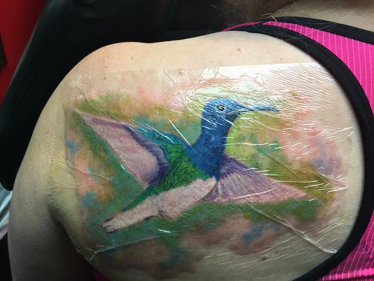 A woman has a tattoo of a hummingbird on her shoulder.