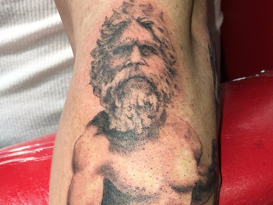 A person has a tattoo of a man with a beard on their leg.