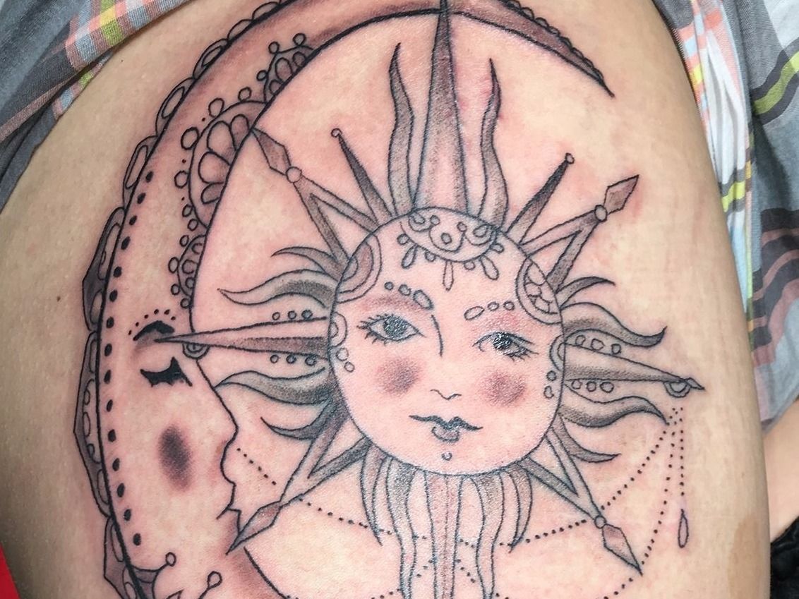 A tattoo of a sun and a crescent moon on a person 's shoulder.