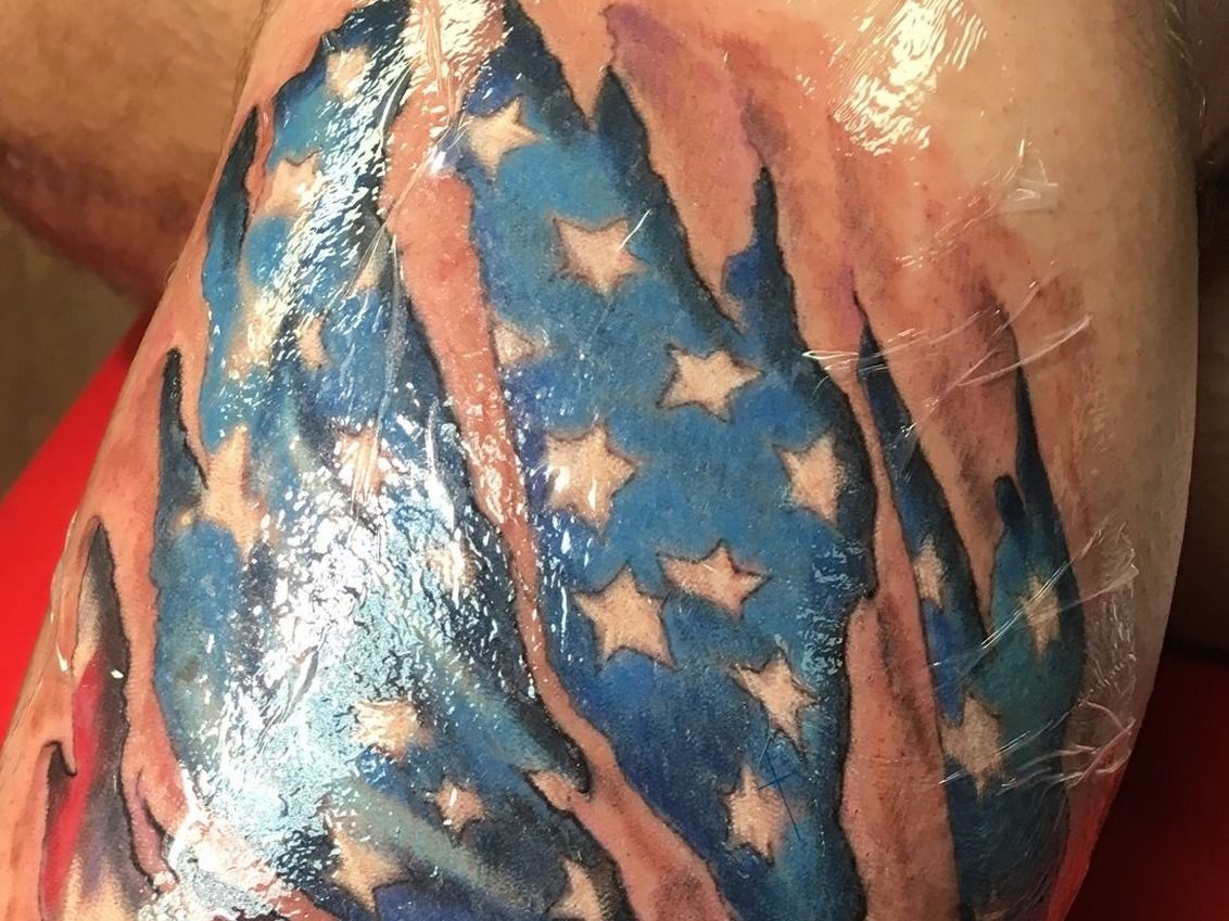 A person has a tattoo of an american flag on their arm.