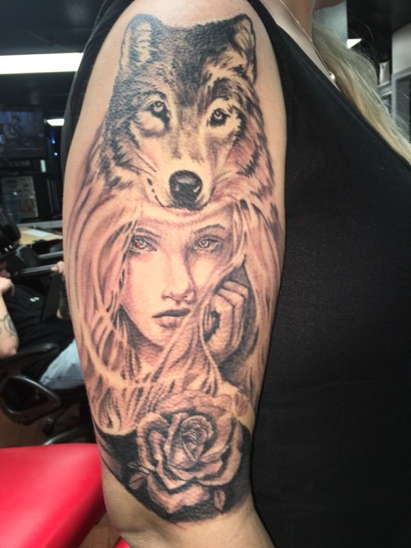 A woman has a tattoo of a woman and a wolf on her arm
