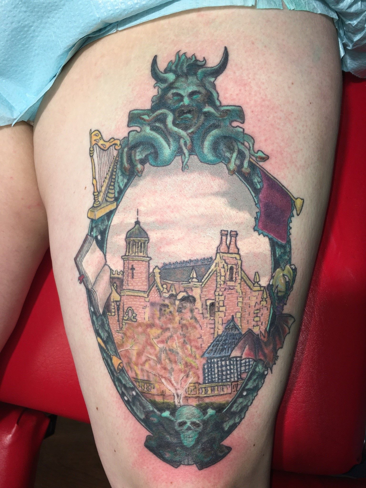 A woman has a tattoo of a castle on her thigh.