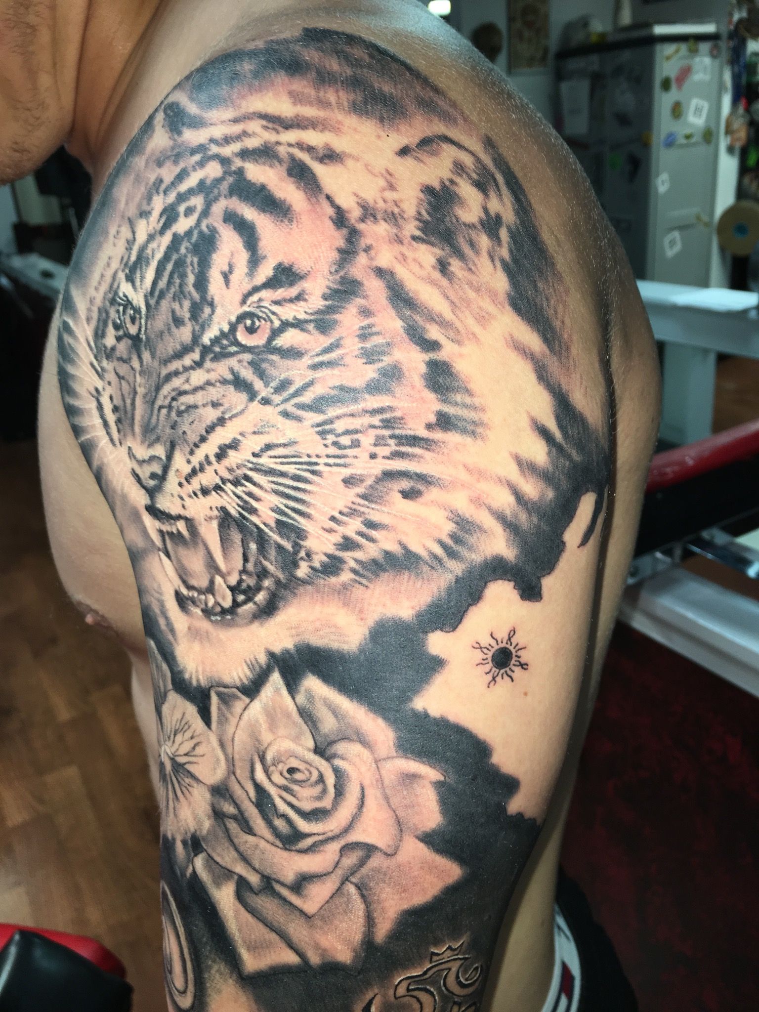 A man has a tattoo of a tiger and roses on his arm.