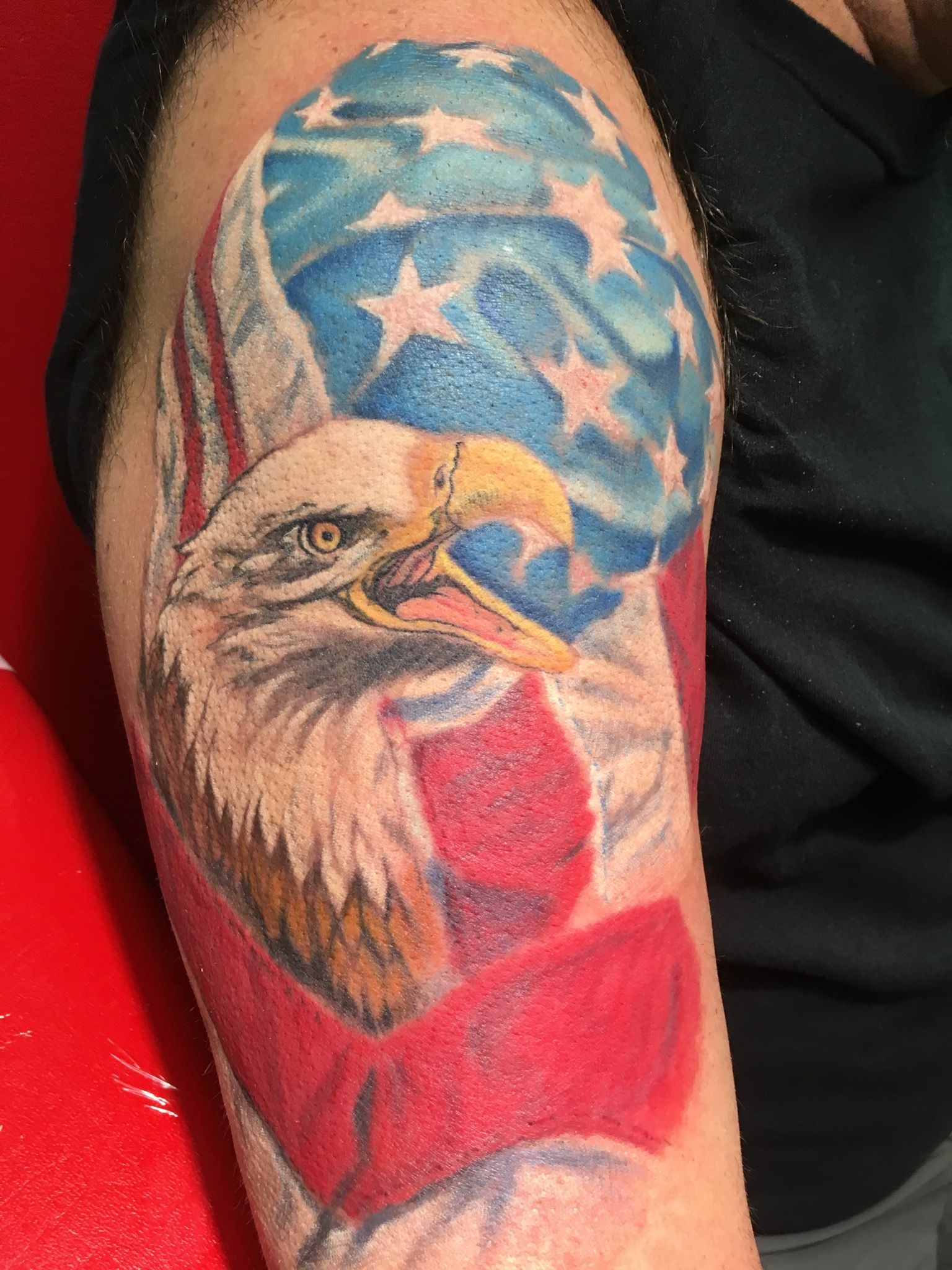 A man has a tattoo of an eagle and an american flag on his arm.