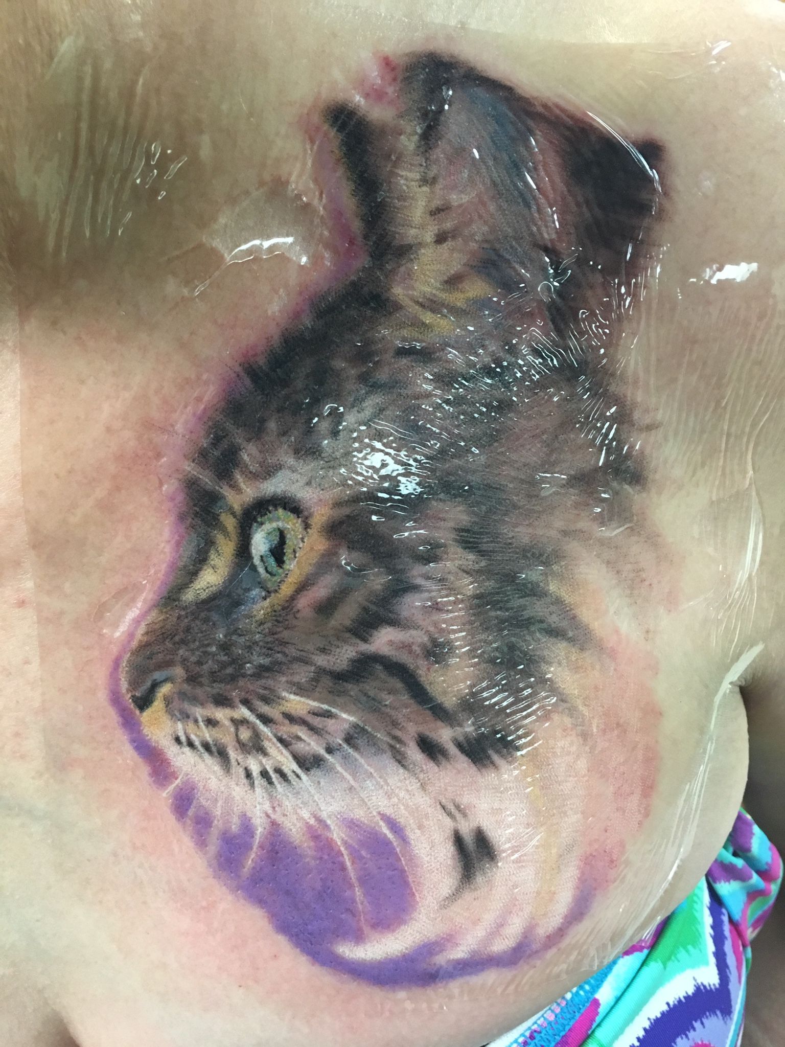 A close up of a tattoo of a cat on a person 's neck.