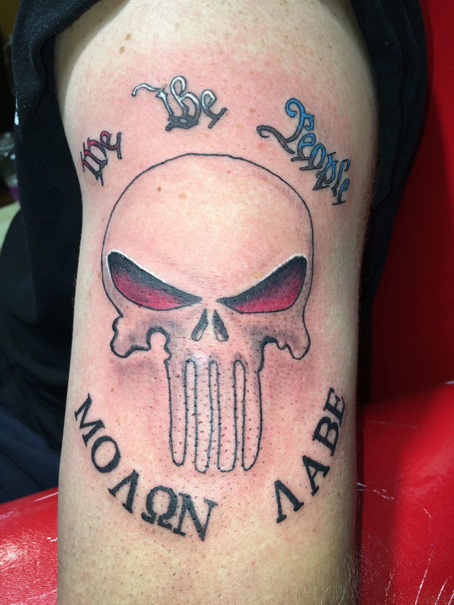 A person has a punisher skull tattoo on their arm.