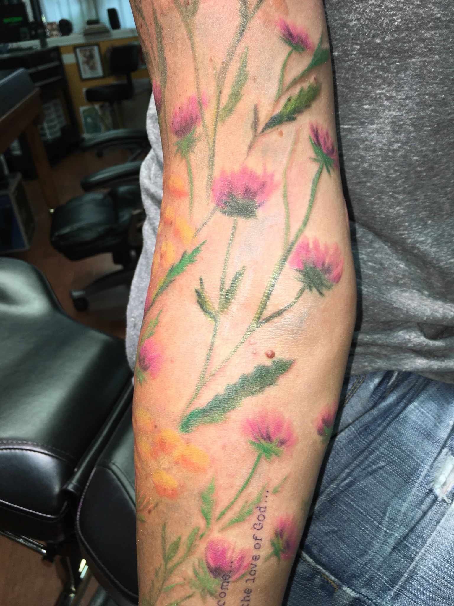 A person has a tattoo of pink flowers on their arm