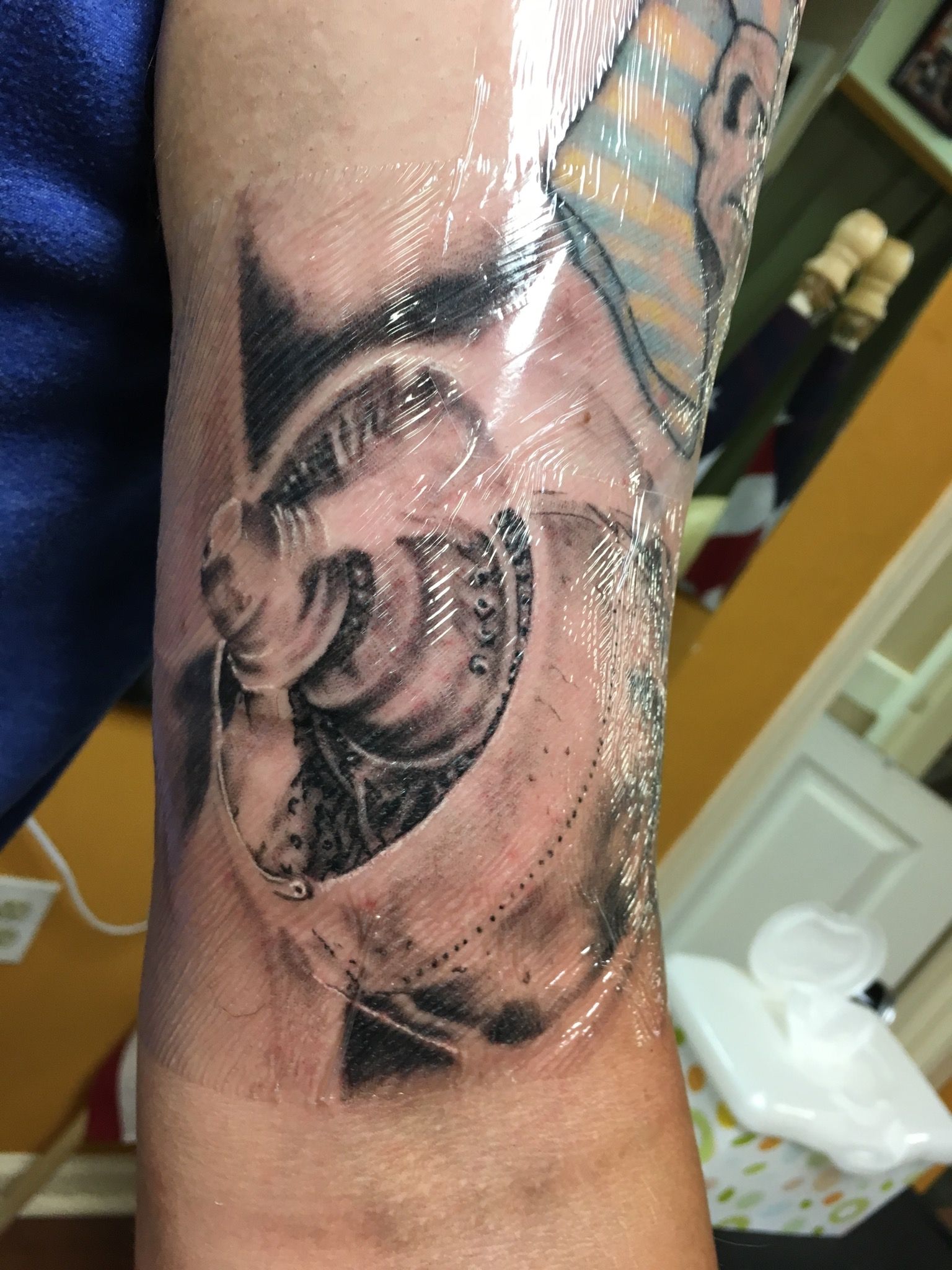 A close up of a tattoo on a person 's arm wrapped in plastic wrap.