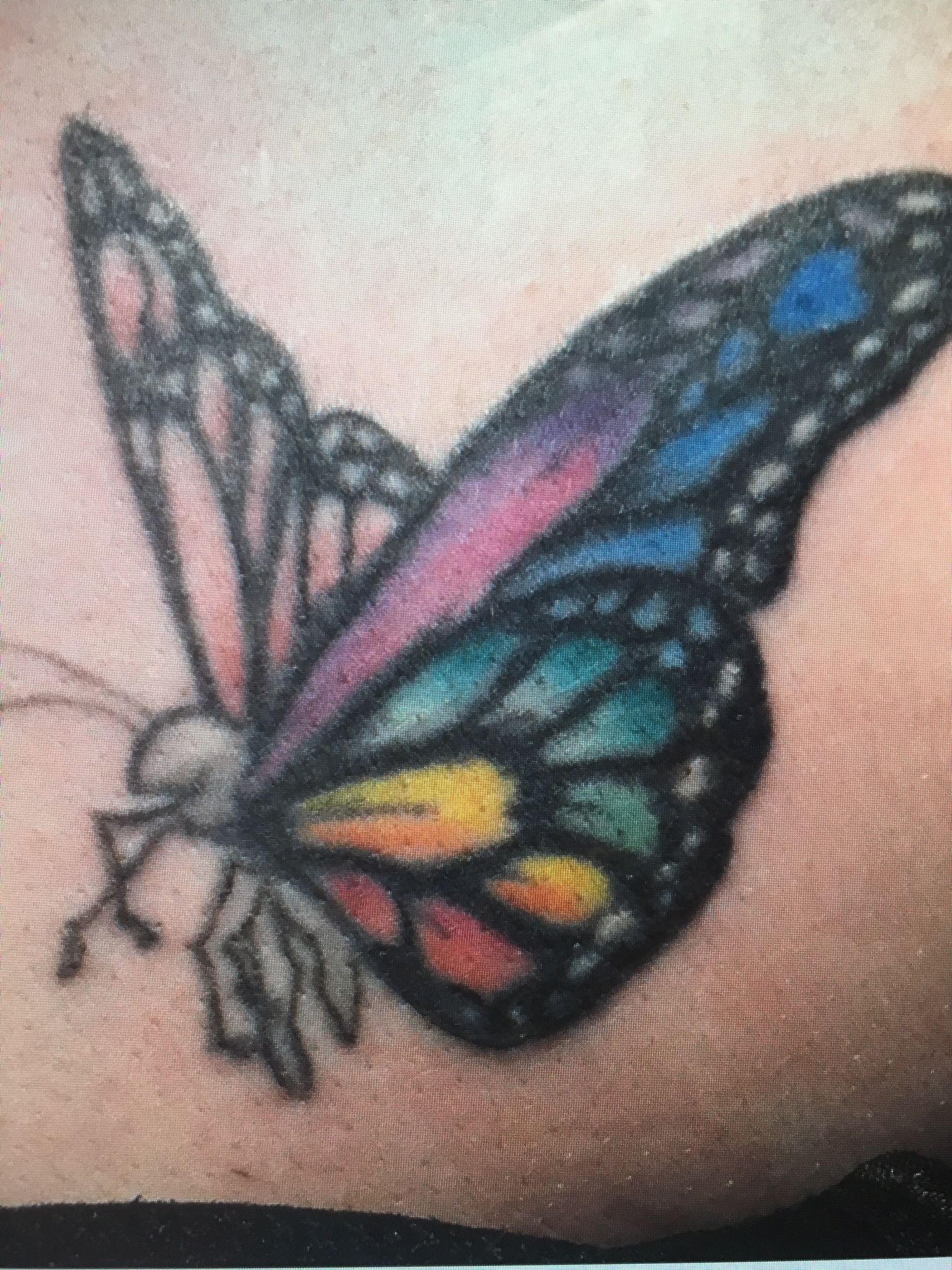 A close up of a butterfly tattoo on a person 's arm.