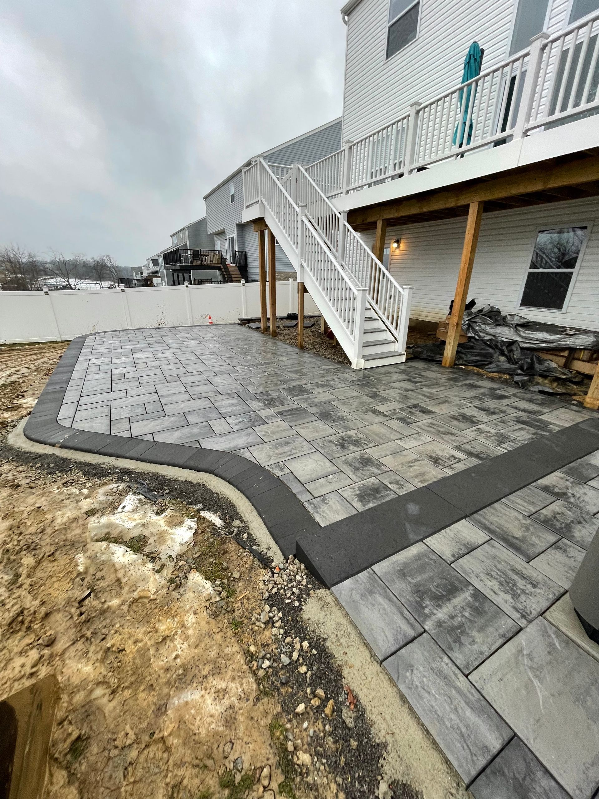 Outdoor patio with gray pavers, white stairs, and a small pond beside a building