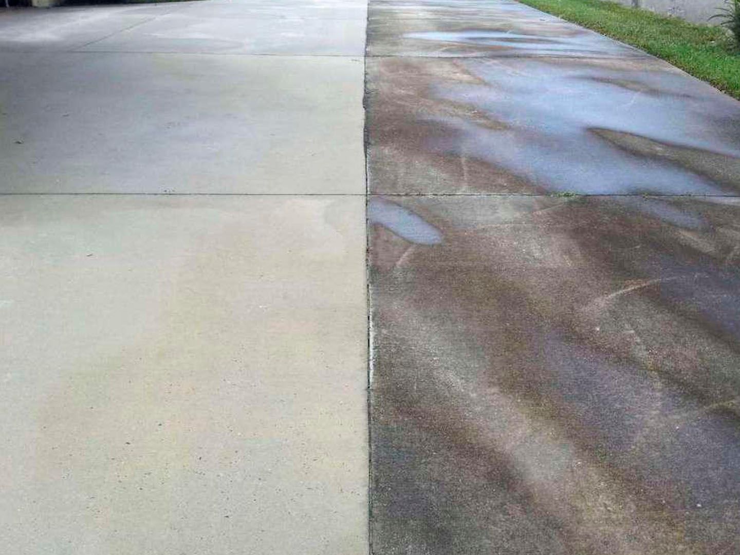 Wet concrete driveway beside a dark asphalt road with puddles and water stains