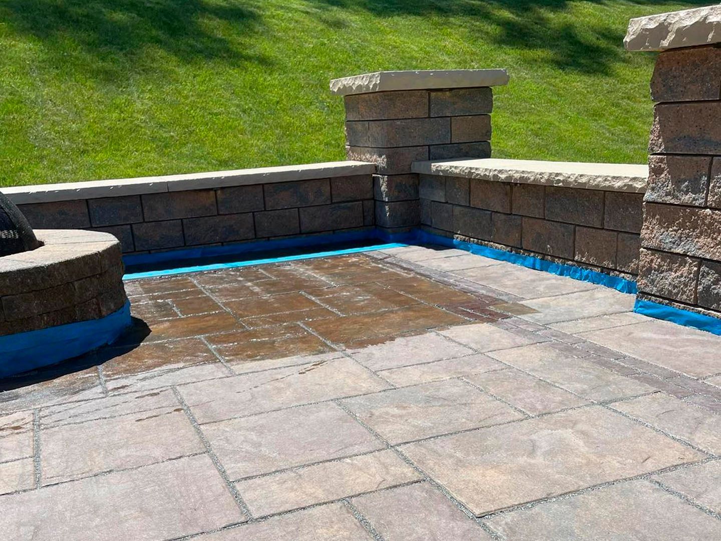 Stone patio with built-in seating and a grassy hillside in the background