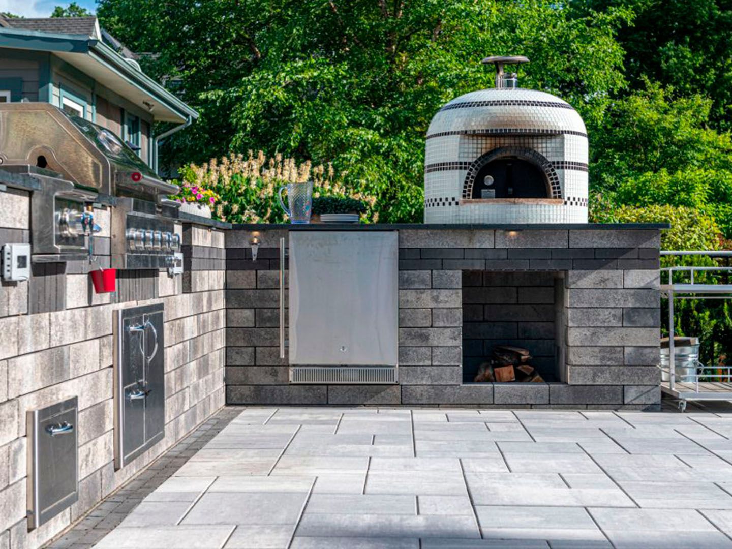 Outdoor brick pizza oven and grilling area with stone counters and paved patio