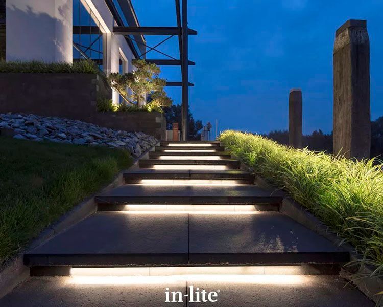 Illuminated outdoor stone steps with built-in lights beside a modern house at dusk