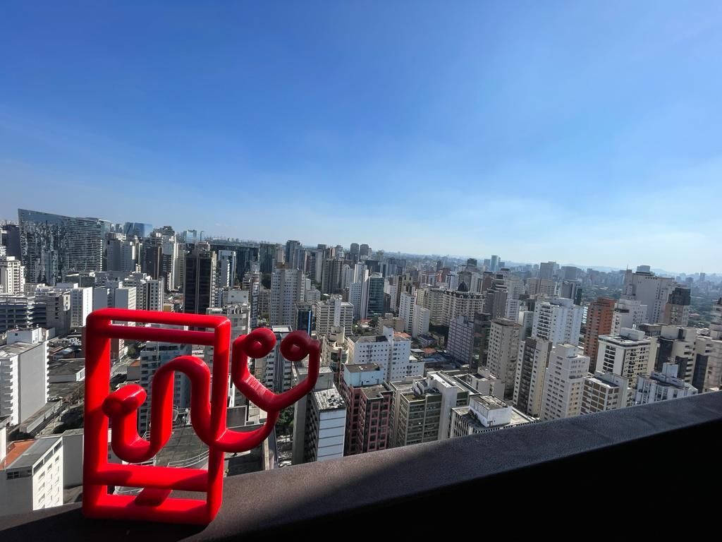 City skyline viewed from a rooftop terrace with a red bench in the foreground.