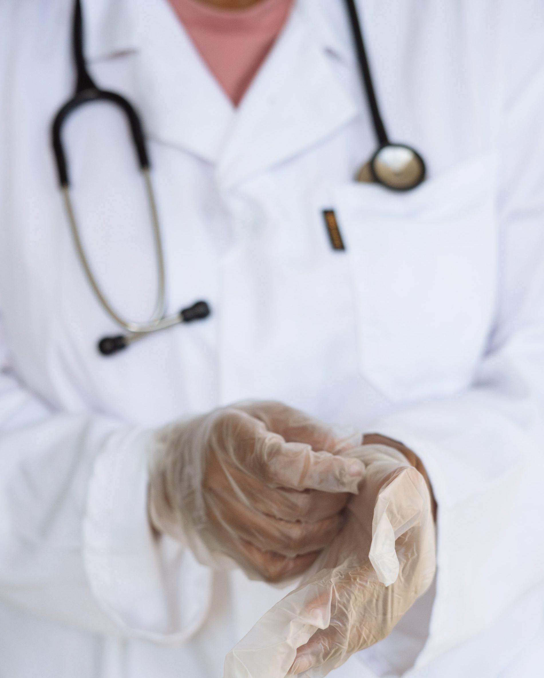 Doctor in white coat and gloves handing a tissue in a clinical setting