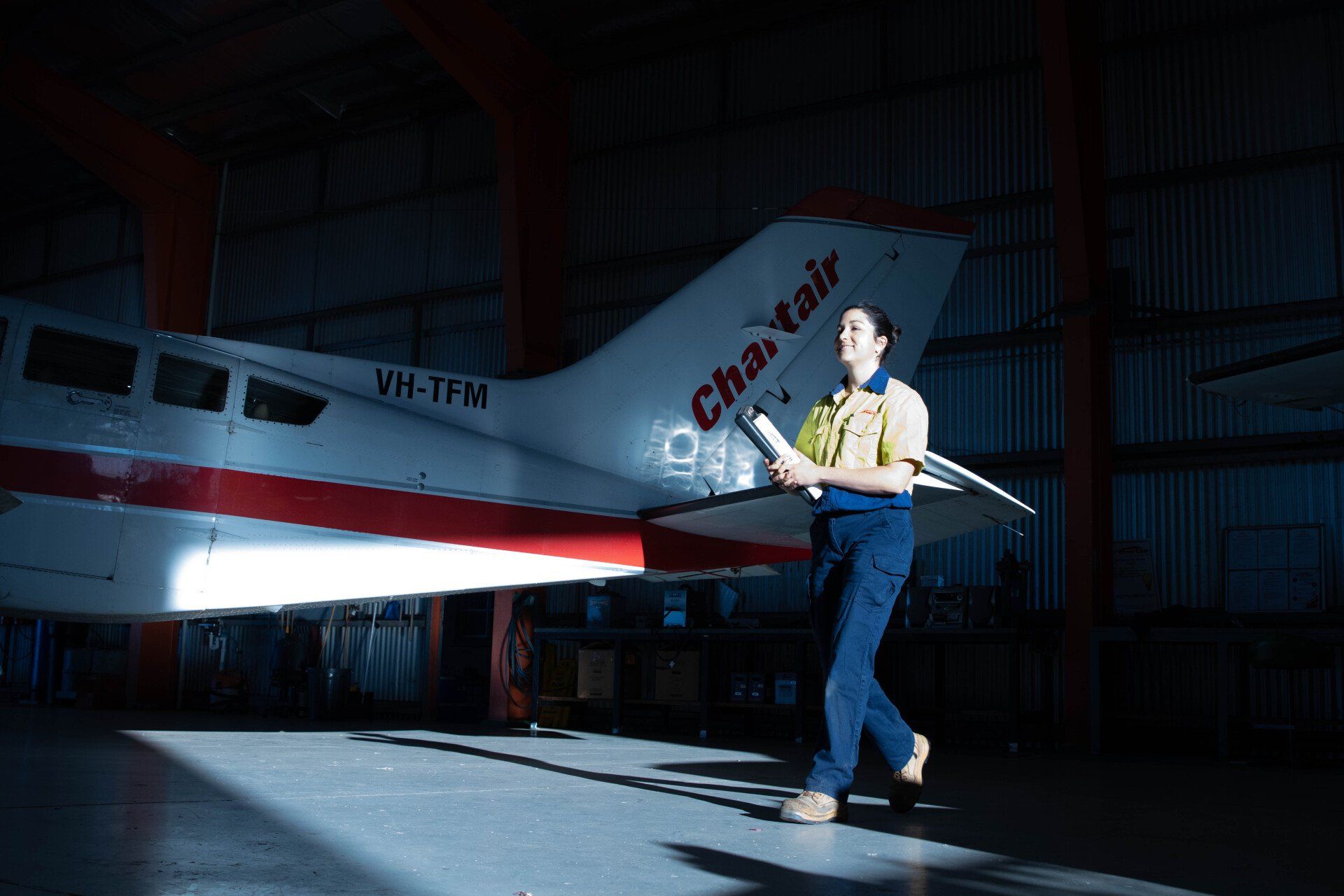 A female engineer is walking past an aeroplane