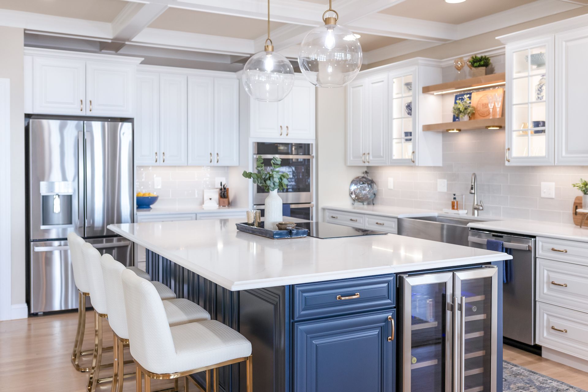 Calacatta Miraggio Cielo Q Quartz Countertops, Armonie Picadilly Avorio Glossy Tile Backsplash, Waypoint Painted Linen Perimeter Cabinets, Painted Navy Island Cabinets, and Maple Rye Floating Shelves