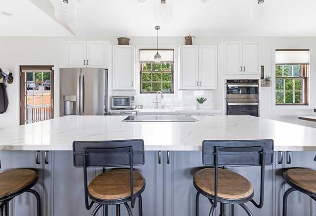 Waypoint Painted Boulder Island Cabinet, Waypoint Painted Pewter Perimeter Cabinets, and Calacatta Laza Q Quartz Countertops