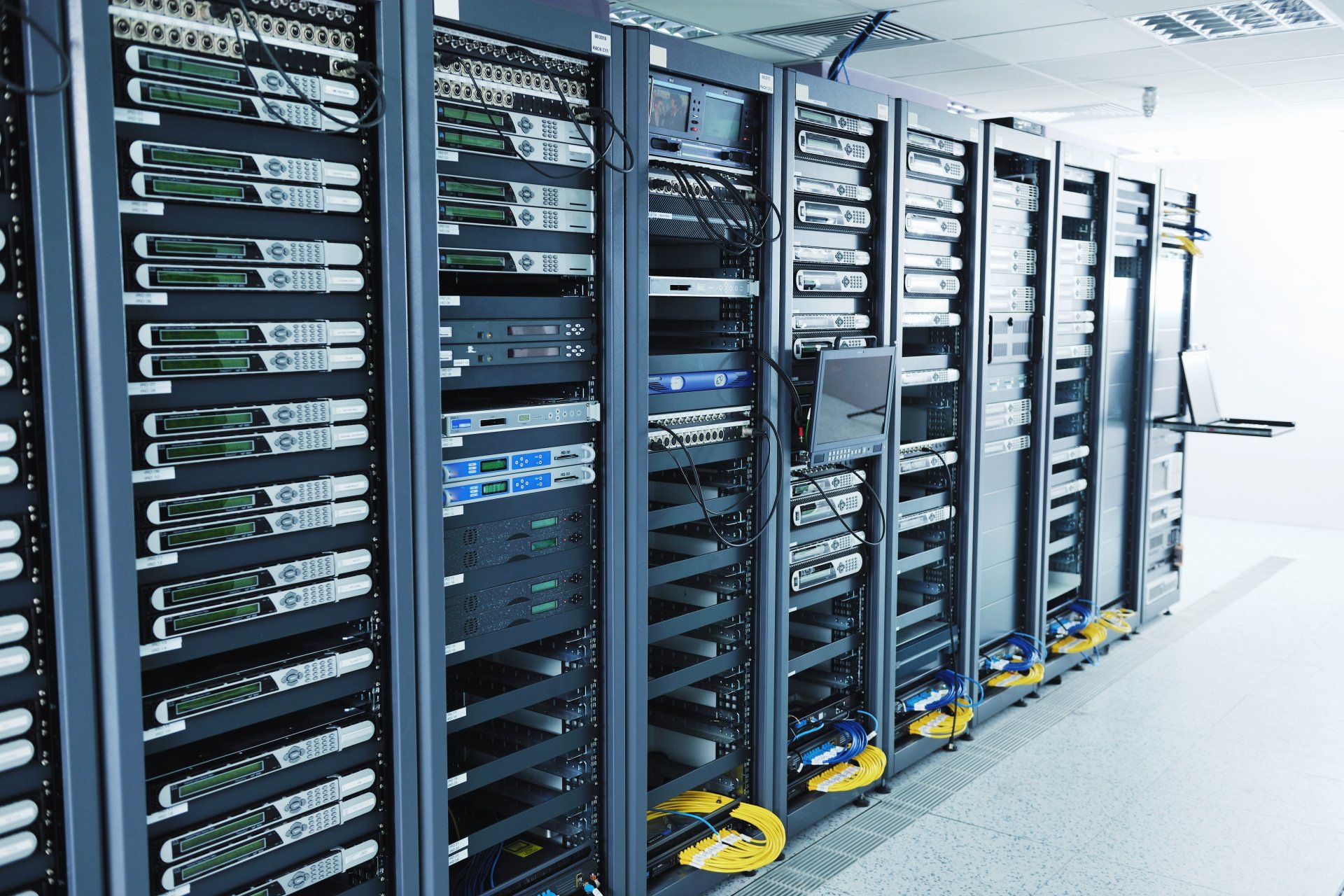 Server racks in a data center, rows of black cabinets with various electronic equipment.