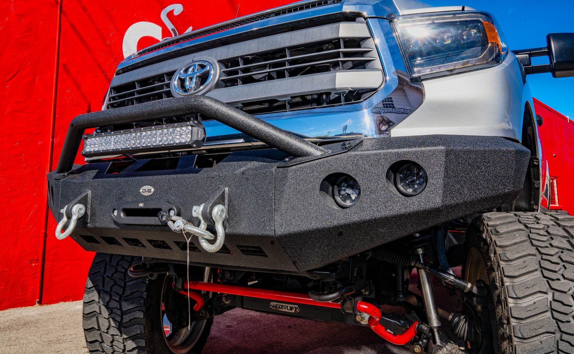 A toyota tundra is parked in front of a red wall.