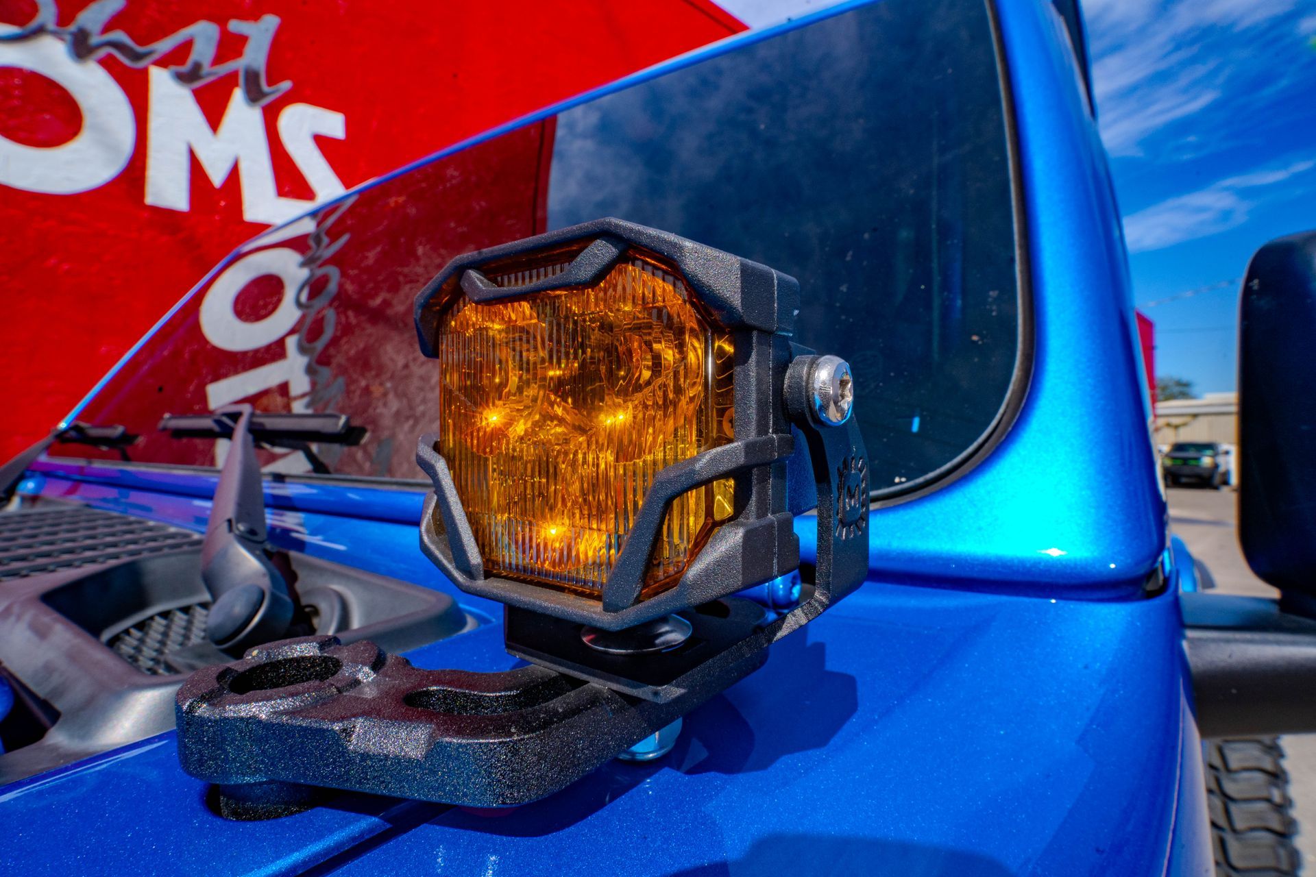 A blue jeep with a yellow light on the hood.