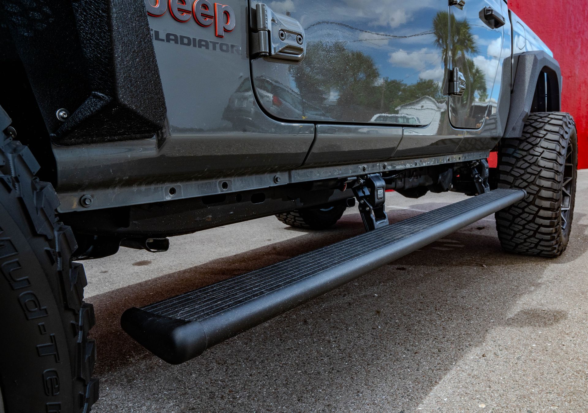 A jeep gladiator with a side step is parked on the side of the road.