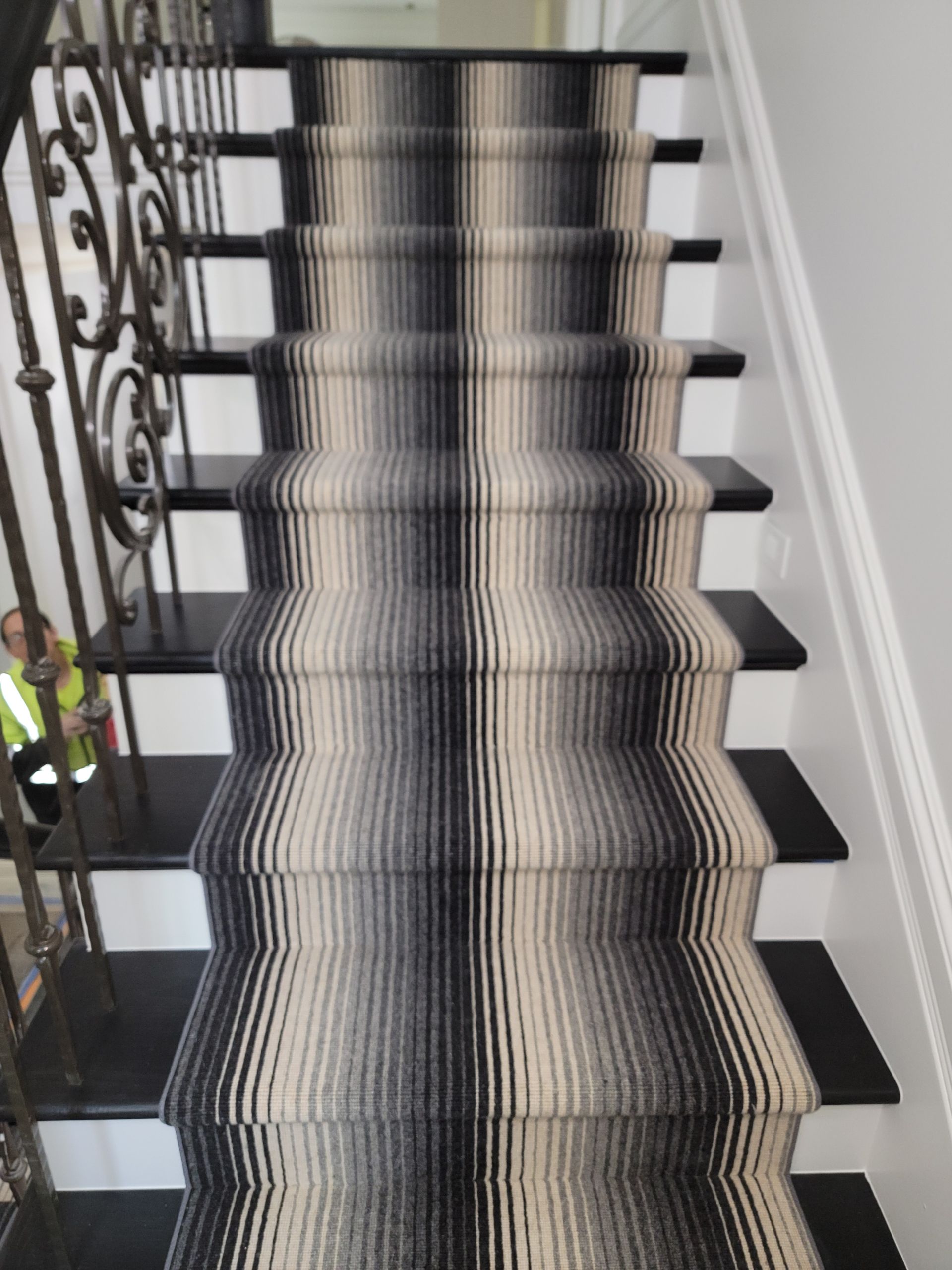 Black-and-white striped staircase runner on indoor stairs with decorative iron railing