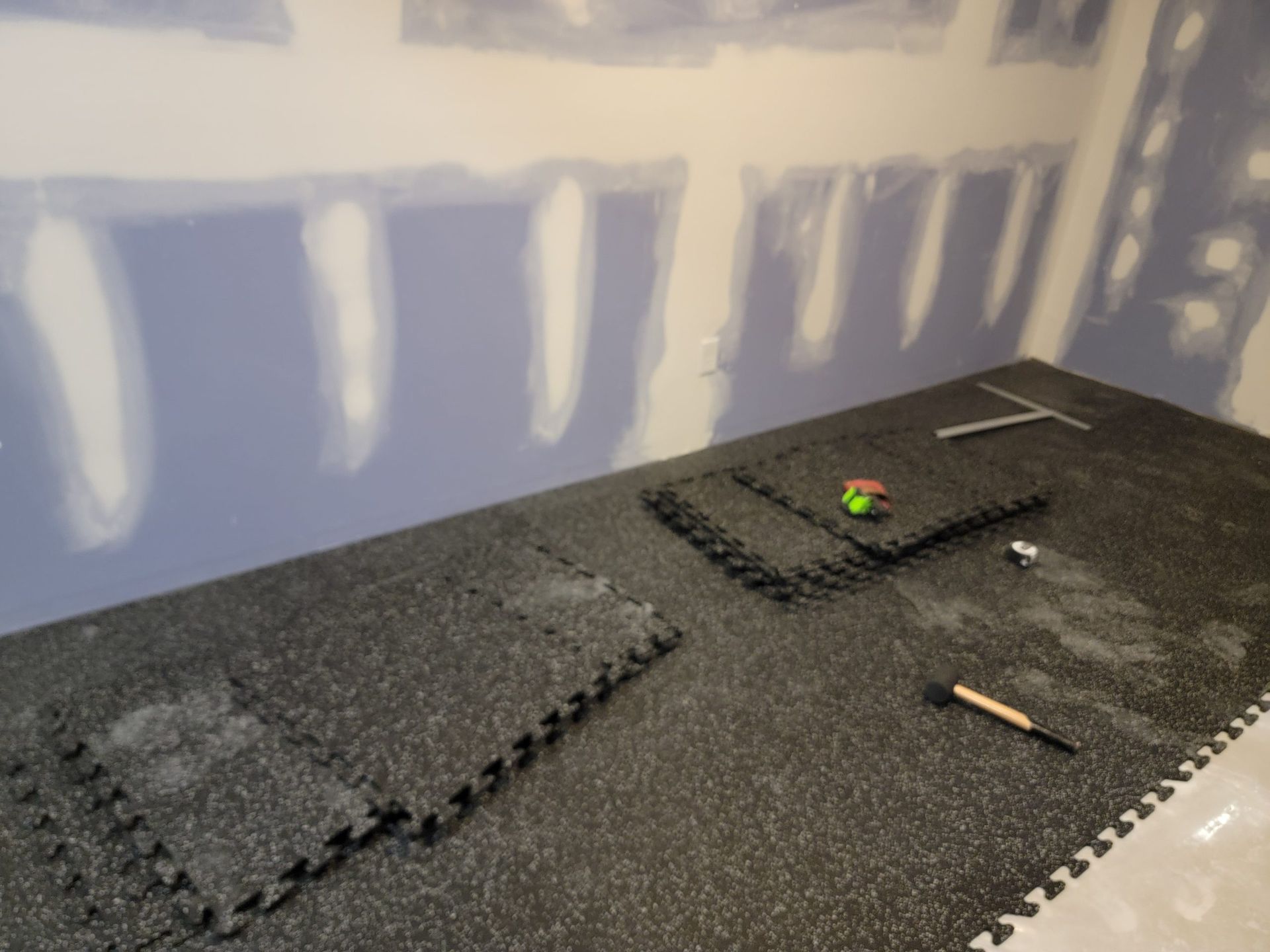 Partially finished foam-lined room with a green ball and a pencil on a dark floor mat.