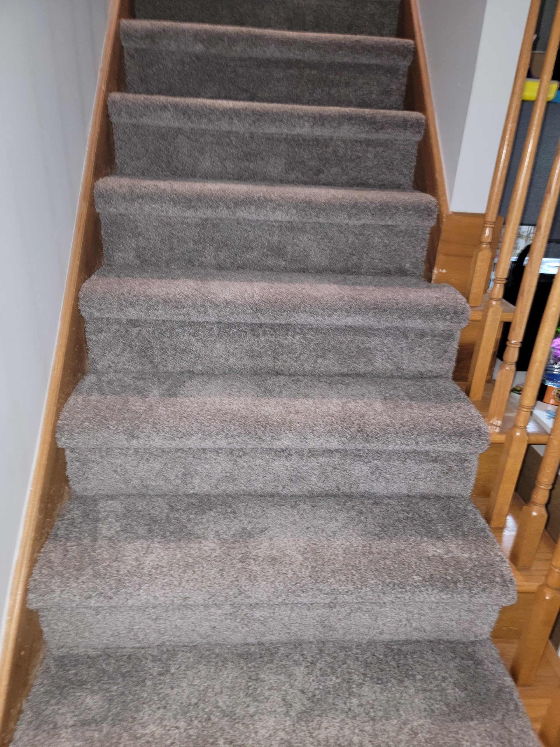 Carpeted indoor staircase with wooden banisters and beige walls