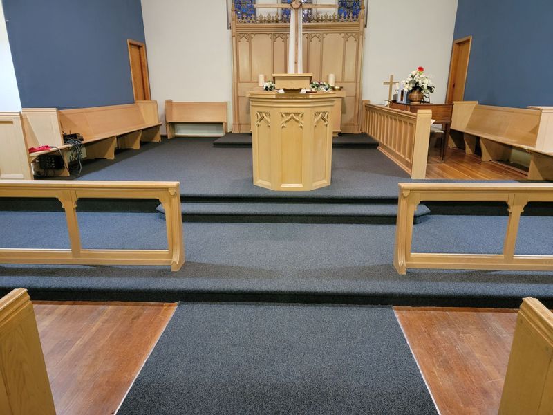 Church sanctuary with central pulpit, pews, and blue carpeted steps