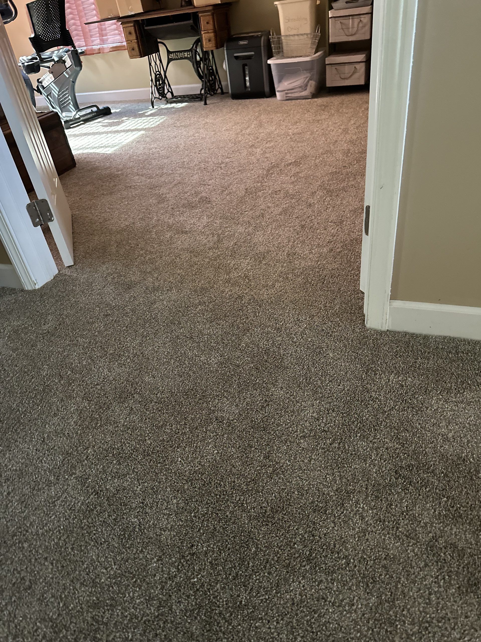 Carpeted hallway leading into a room with a table, chair, and storage bins.