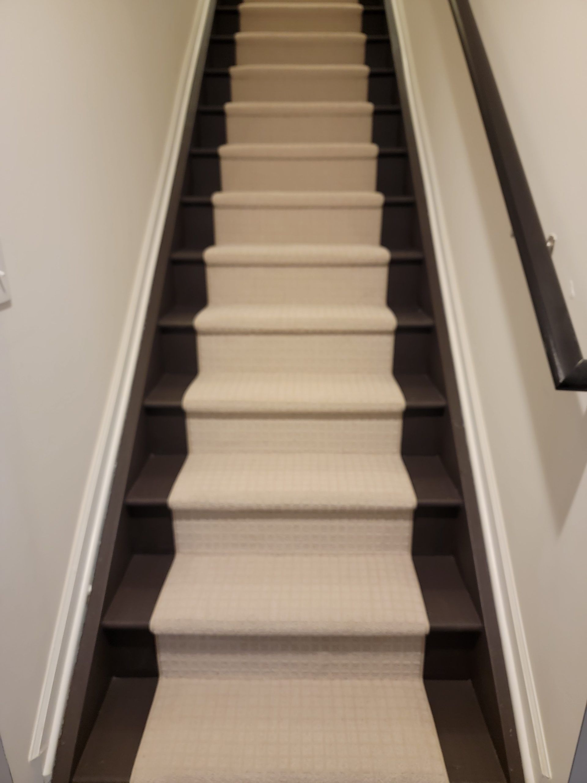 Narrow indoor staircase with beige carpet and white walls leading upward
