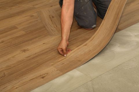 Person laying a wood-look floor plank over a cushioned underlayment during installation