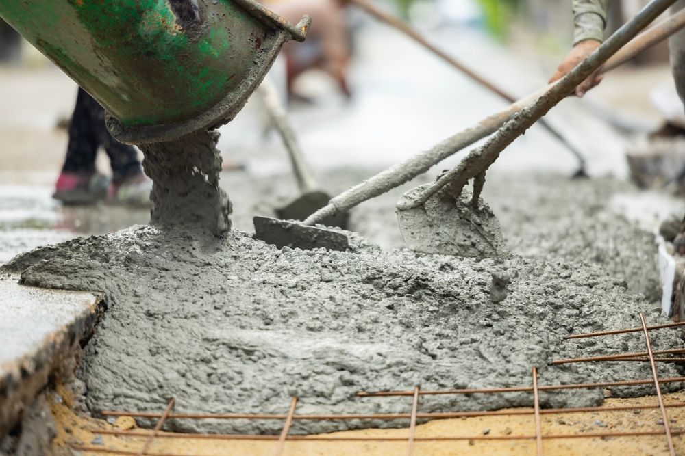 Wet concrete being poured and smoothed at a construction site