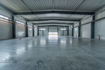 Empty industrial warehouse with a polished concrete floor and metal walls, viewed from the center