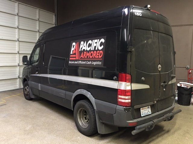 Black Pacific Armored van parked indoors, with company logo on the side.