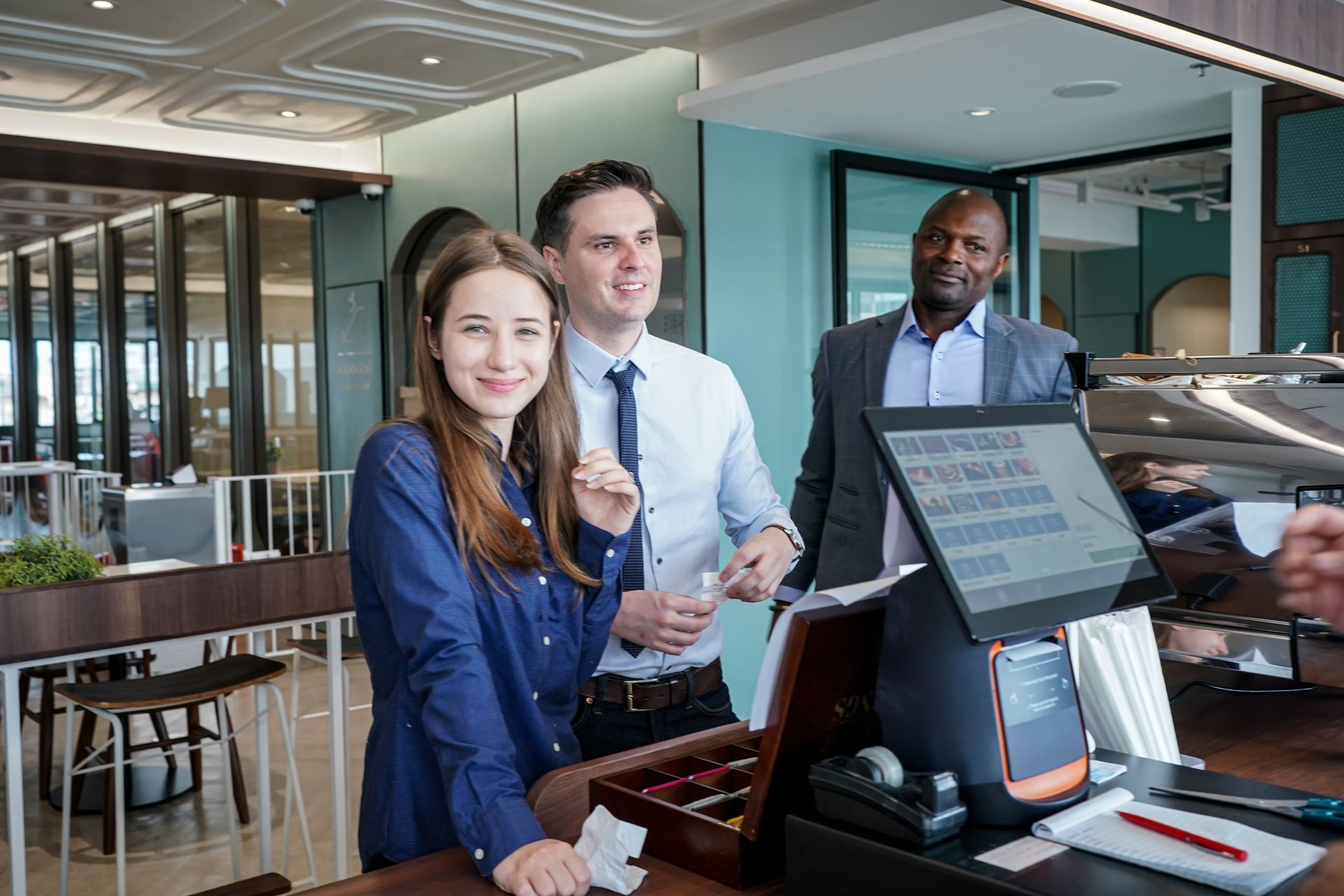 A group of people are standing around a counter in a restaurant.