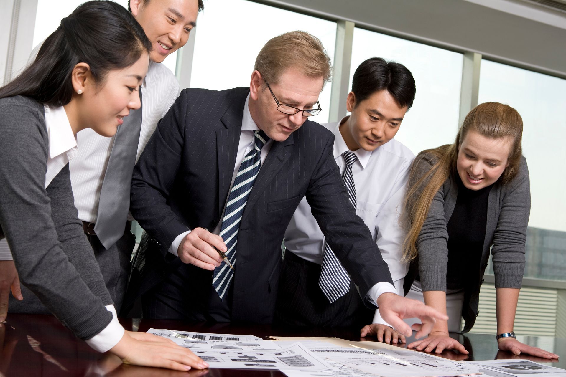 A group of business people are looking at a map on a table.