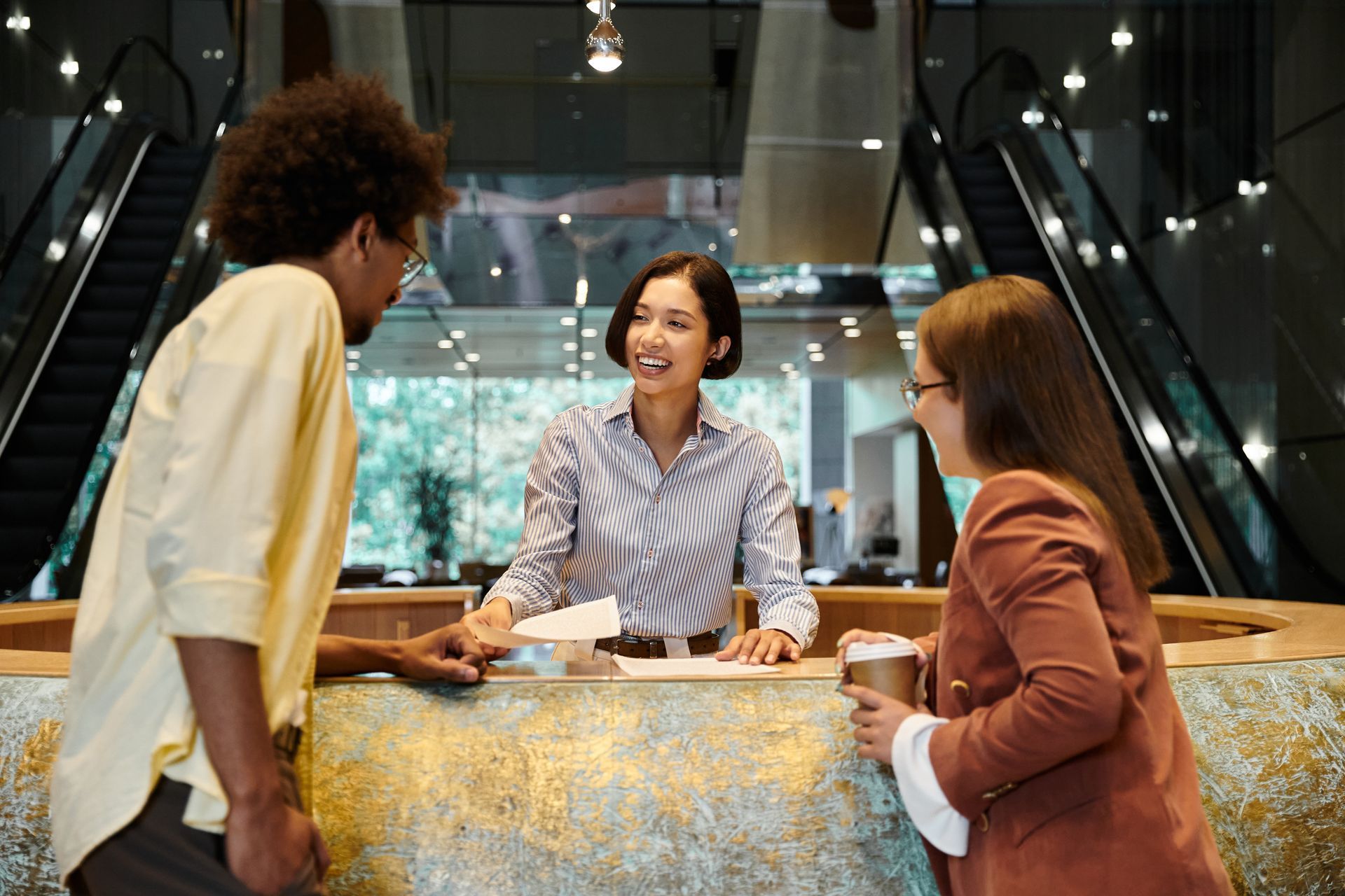 A group of people are standing at a counter in a restaurant talking to a woman.
